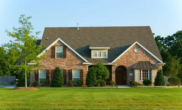 A two-story brick home with brown shutters and a well-maintained lawn after new window installation in Springfield.